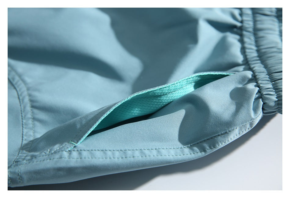 Close-up of a pocket opening with turquoise mesh lining on light blue shorts.
