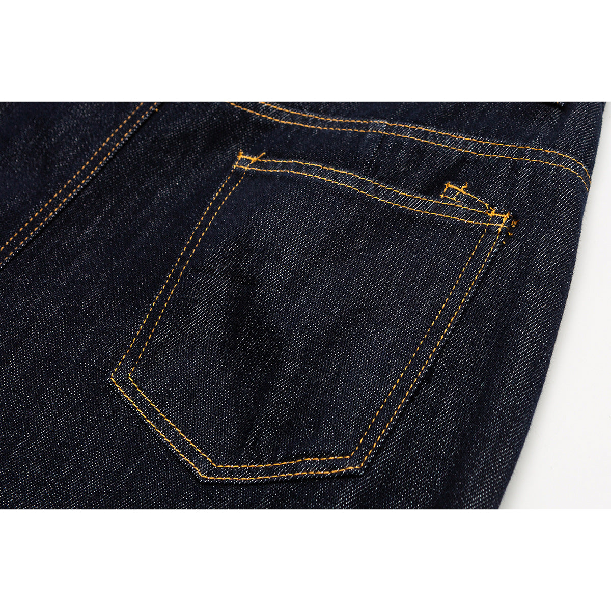 Close-up of a dark indigo jeans back pocket with golden double-row stitching.