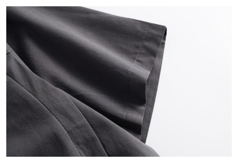 Close-up of a dark charcoal sleeve edge and its stitched hem.