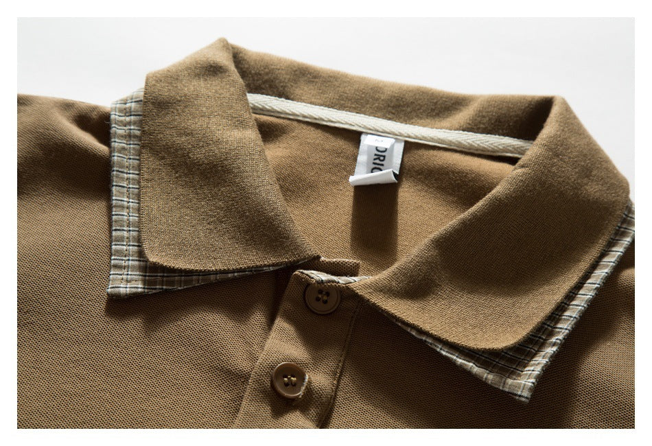 Close-up of a tan polo shirt collar with plaid underside, a two-button placket, and a small neck label.