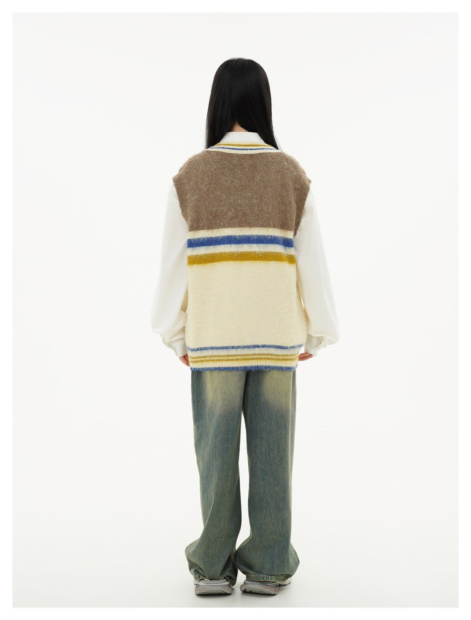 Back view of a model wearing a cream and brown striped V-neck sweater vest over a white shirt and loose jeans.