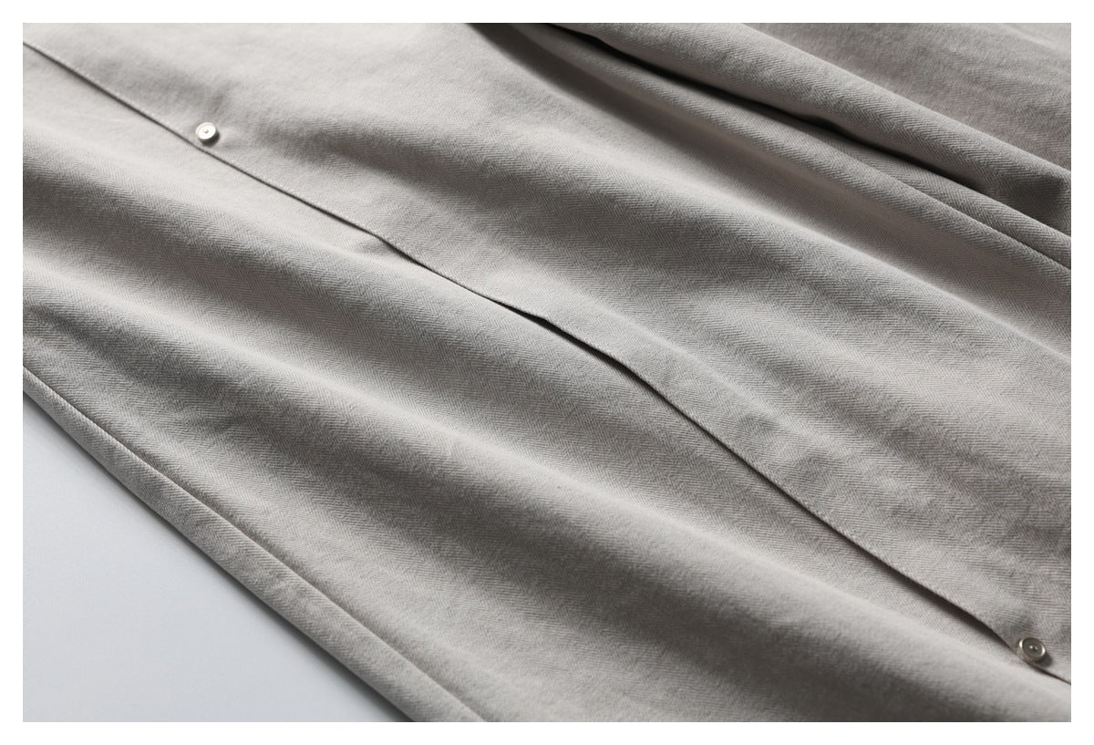 Close-up of gray herringbone trousers showing the front closure and stitched seams.