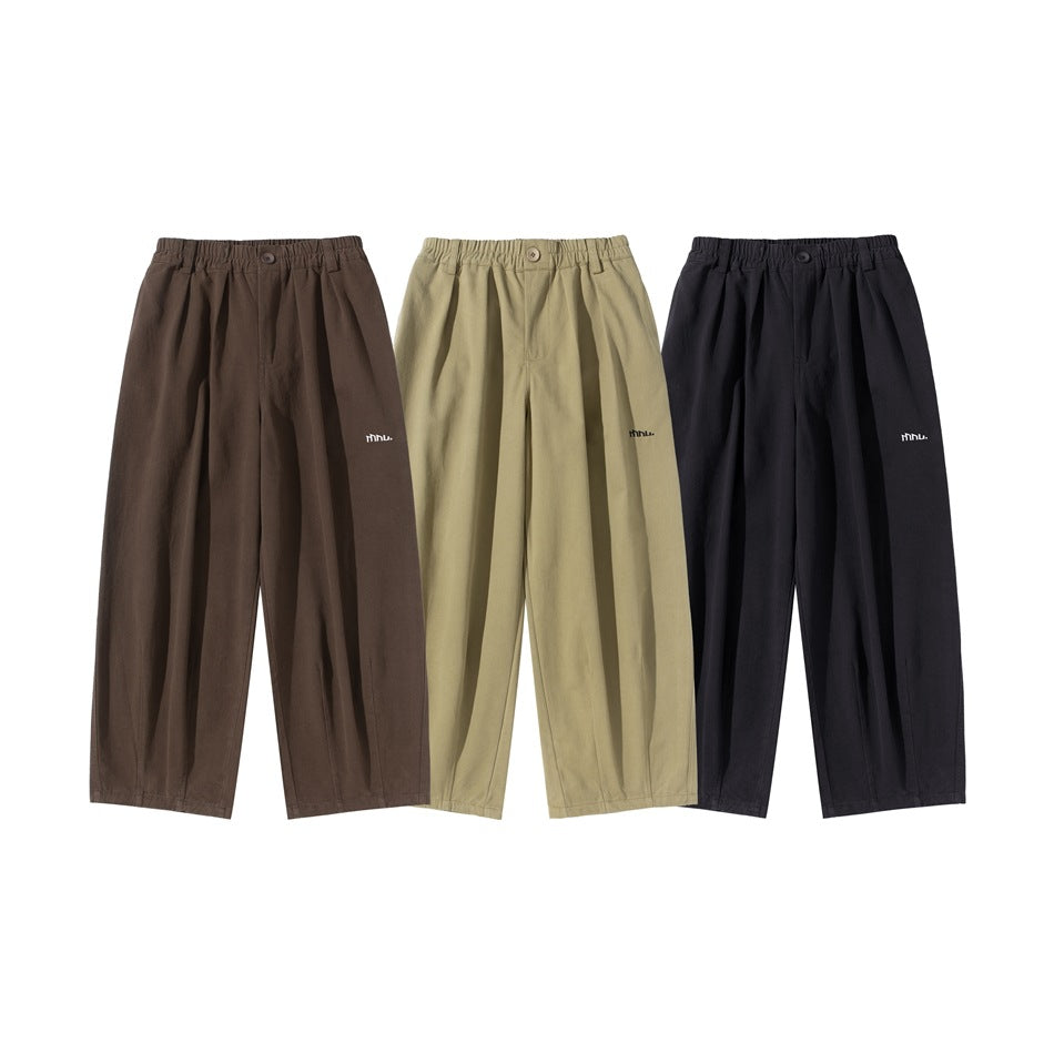 Three pairs of pleated, wide-leg trousers shown from the front in brown, khaki and black.