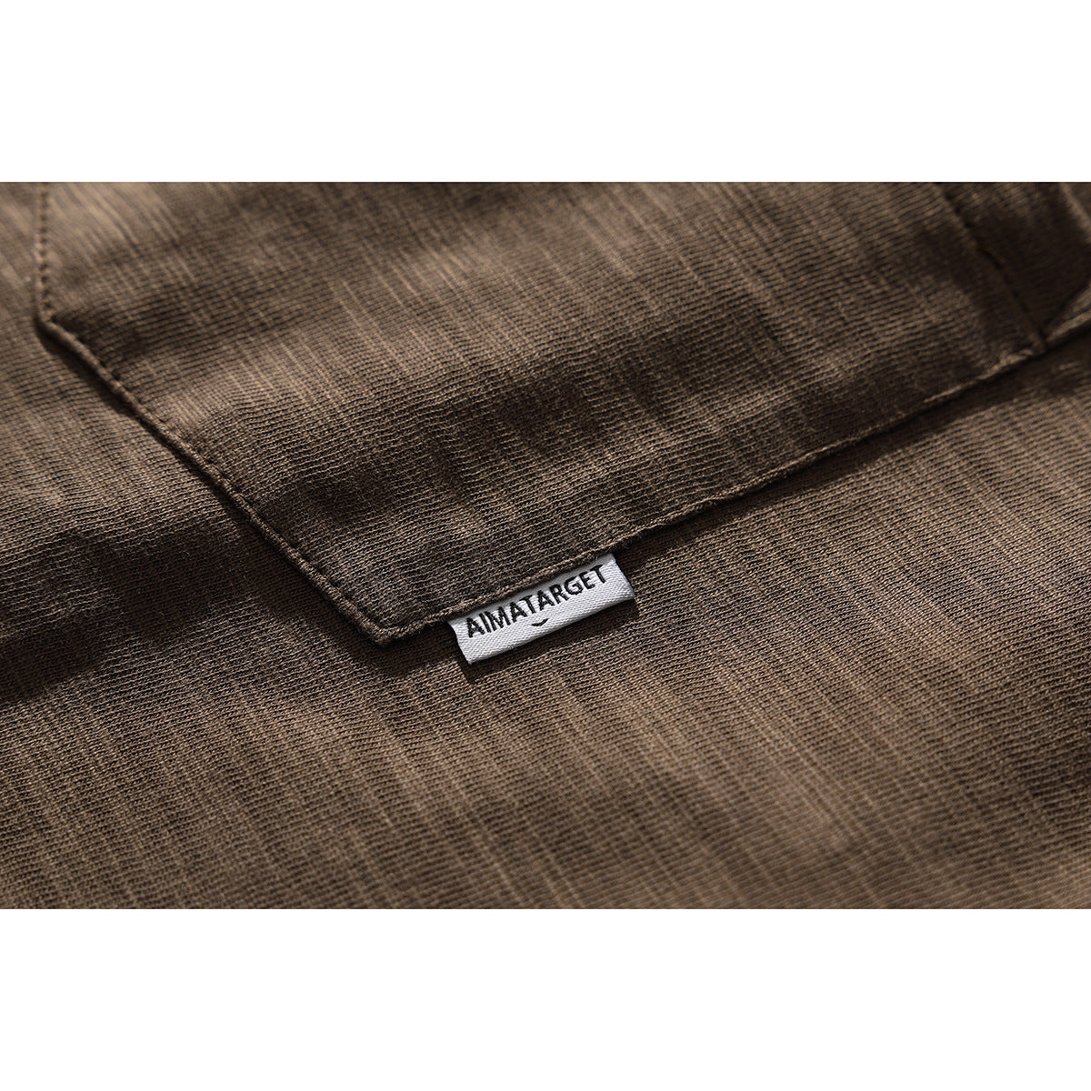 Close-up of a brown heathered T-shirt fabric seam and small sewn brand label.