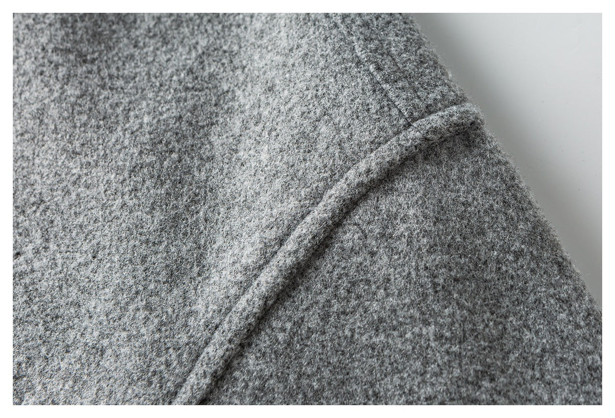 Close-up of a raised seam on gray textured coat fabric.