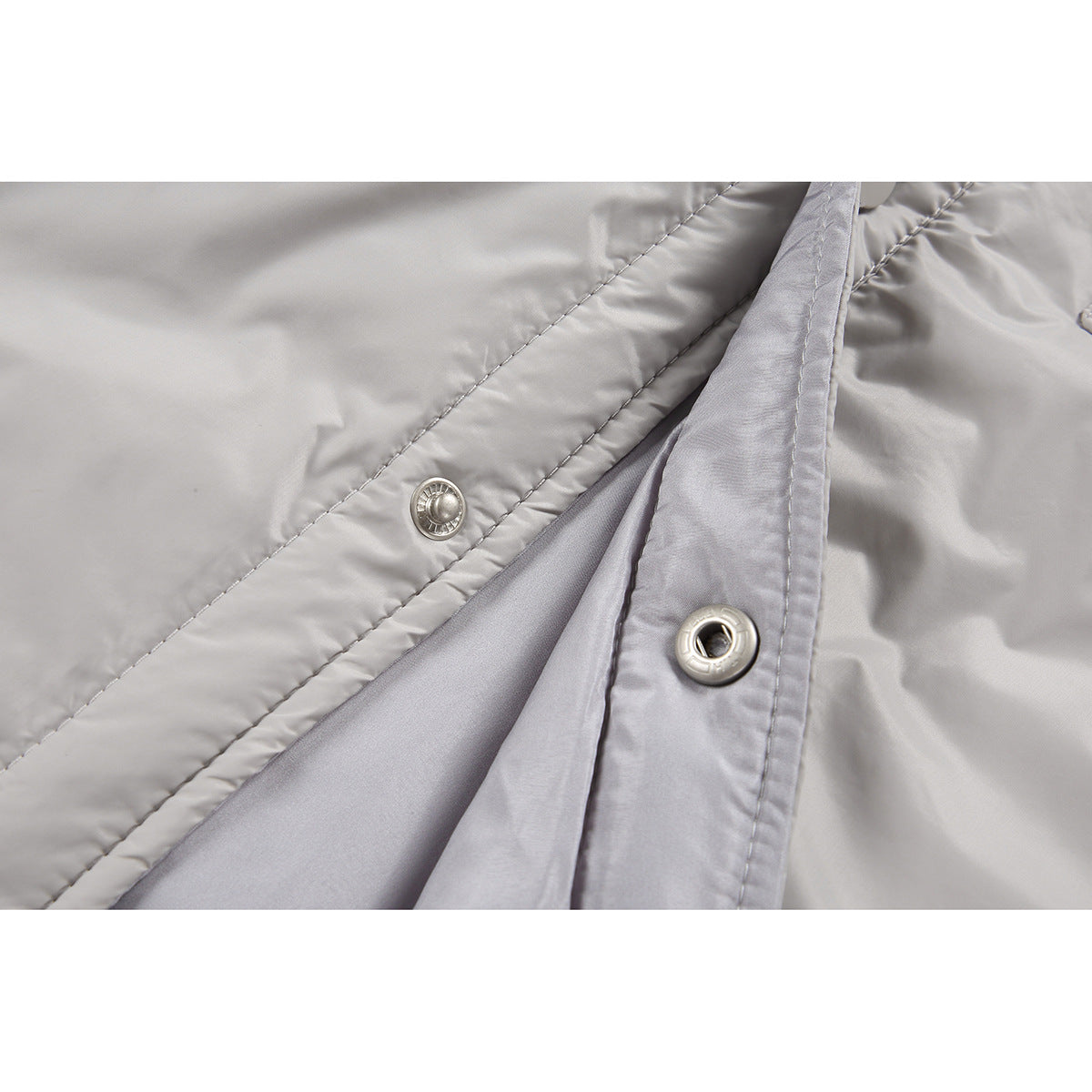 Close-up of the light gray jacket’s open snap-button placket and smooth gray lining.