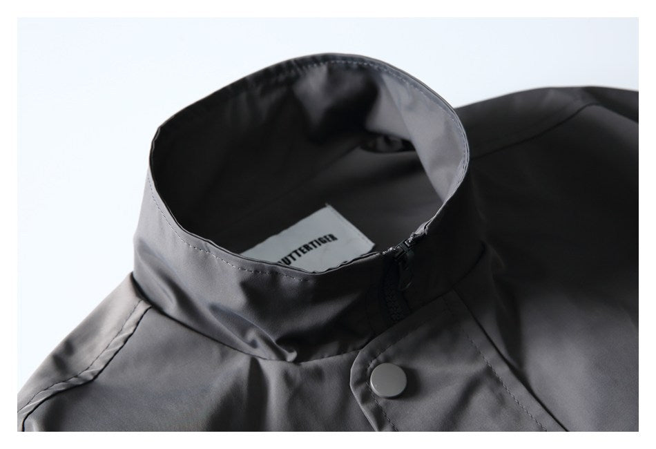 Close-up of a charcoal jacket's stand collar, zipper, snap closure, and inner neck label.