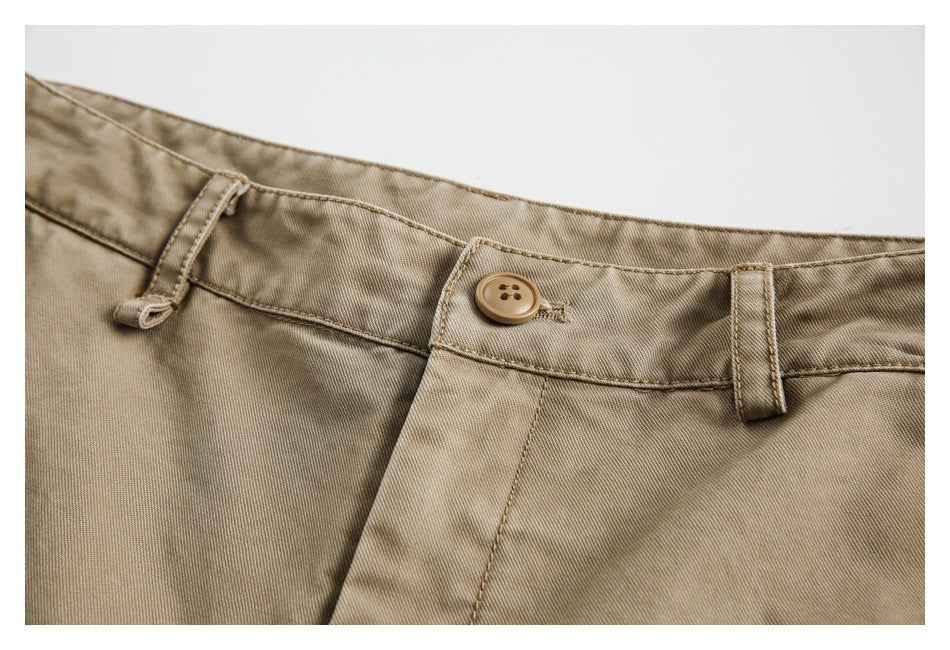 Close-up of tan trousers at the waistband, with a button, belt loops, and fly seam.