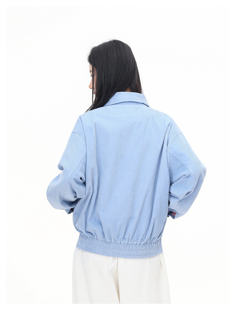 Back view of a model wearing a light blue collared jacket with dropped shoulders and an elasticized hem.