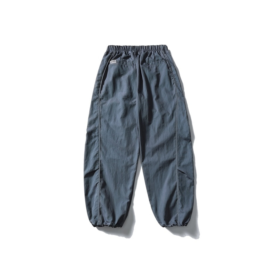 Blue-gray relaxed pants shown from the back, with an elastic waist, two pockets, side seams and gathered cuffs.