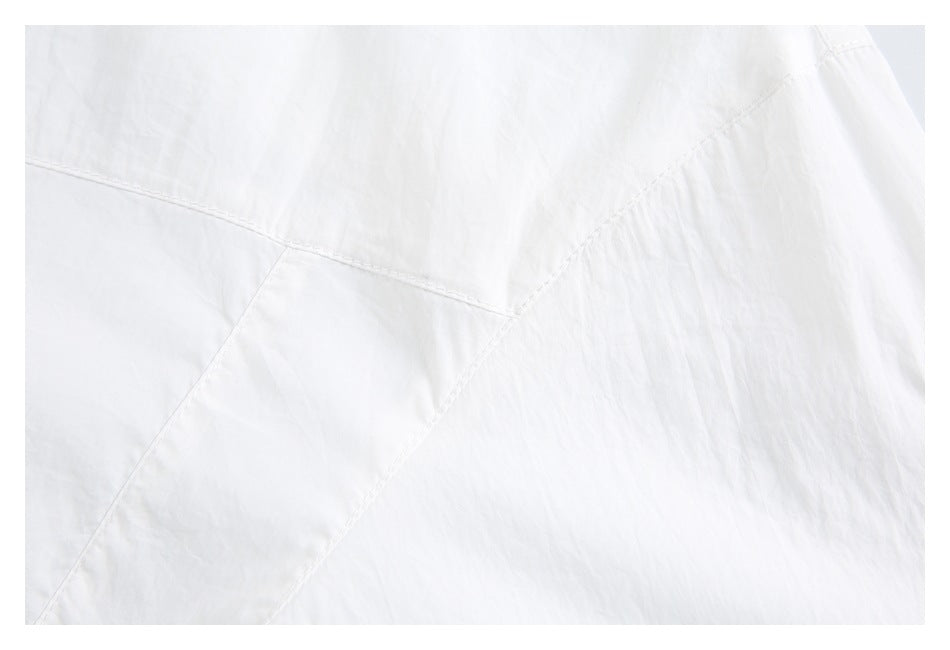 Close-up of white jacket fabric with curved stitched panel seams.