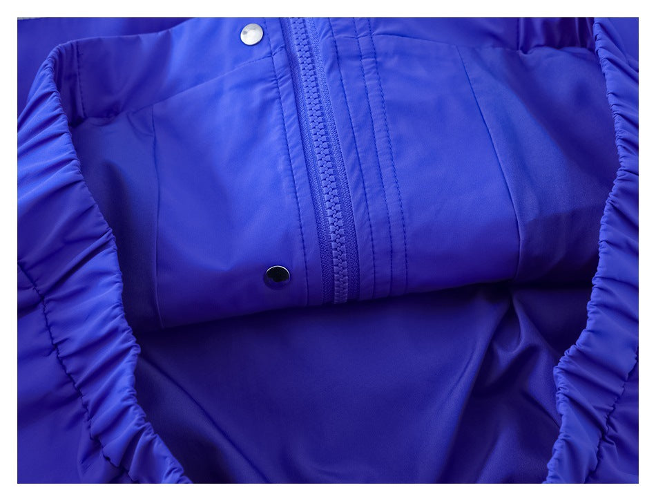 Close-up of a vivid blue garment front with a zipper, snap fasteners, and gathered edges.
