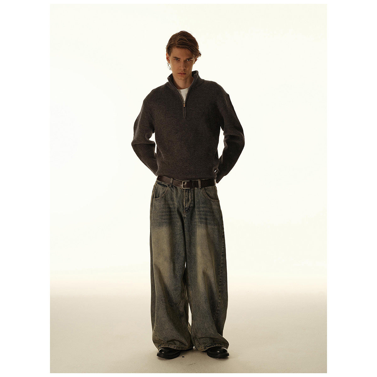 Model wearing a charcoal ribbed quarter-zip sweater with loose gray-wash jeans.