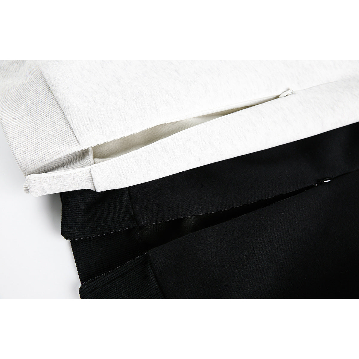 Close-up of light gray and black sweatshirt fabric with zippered side pockets.