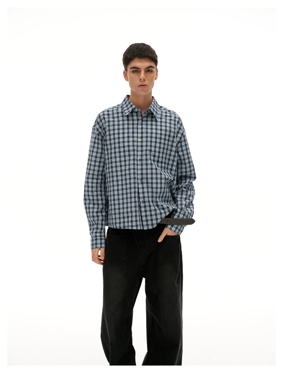 Model wearing a blue-gray plaid button-up shirt with black wide-leg trousers, front view.