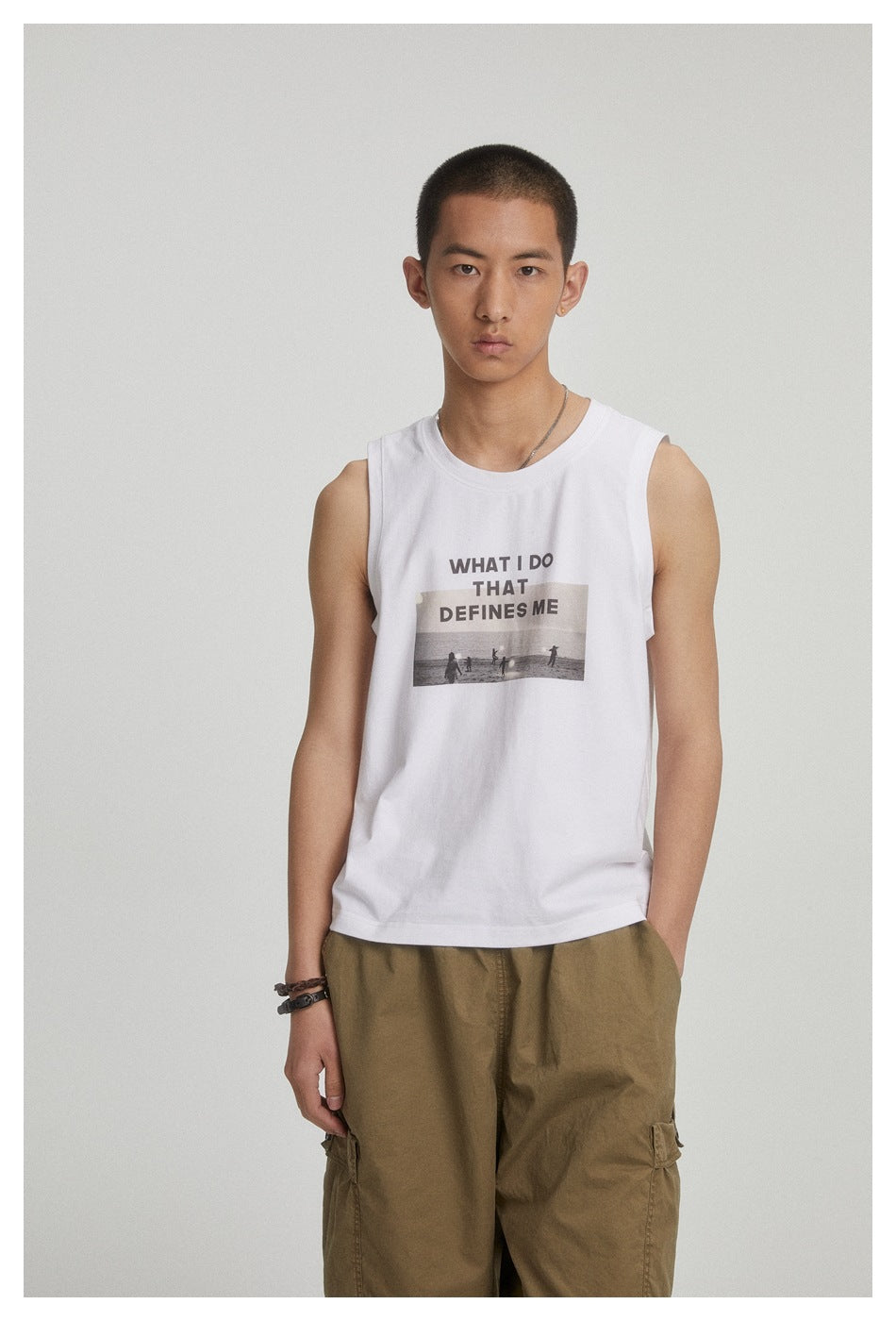 Model wearing the white sleeveless graphic tank top with olive cargo pants, front view