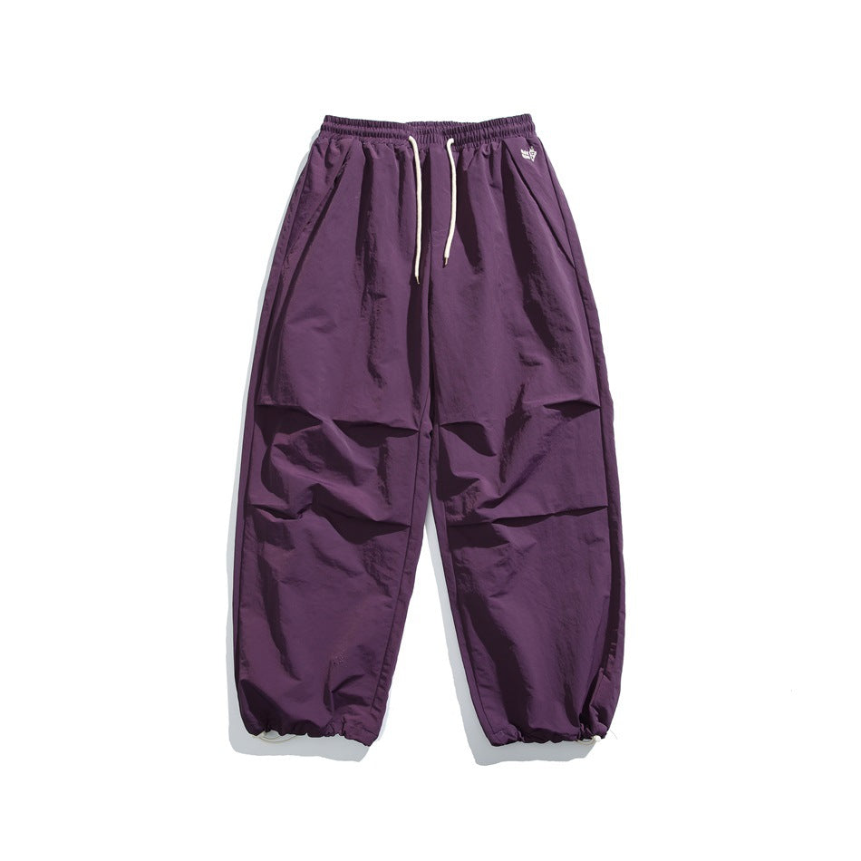 Purple wide-leg drawstring pants with cream cords, pleated knees and drawcord hems, flat lay