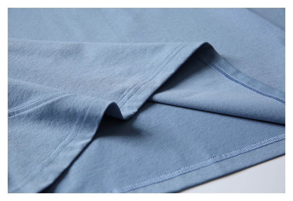 Close-up of the blue garment's folded hem and overlocked stitching.