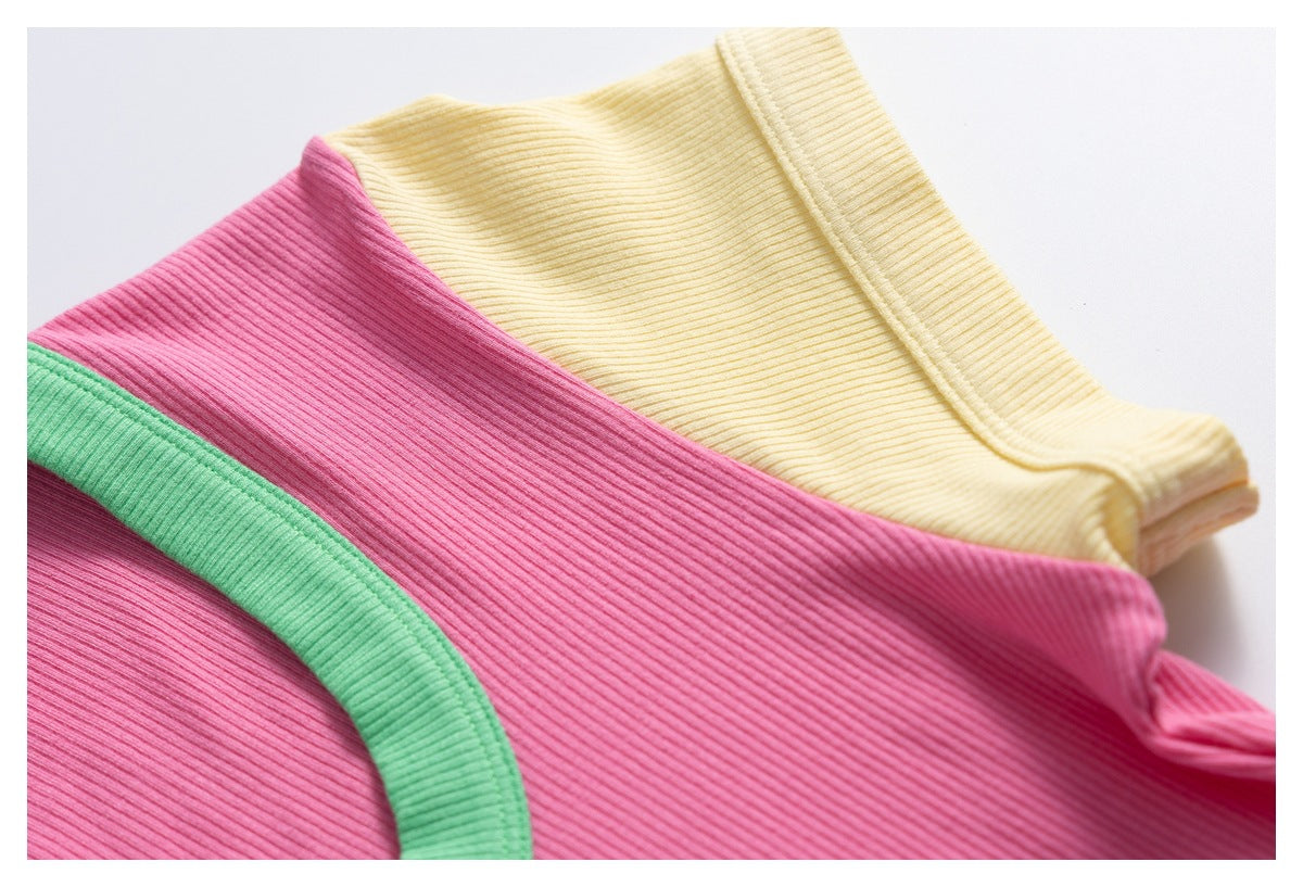 Close-up of folded ribbed shirts in pink and pale yellow, with a green-trimmed neckline visible.