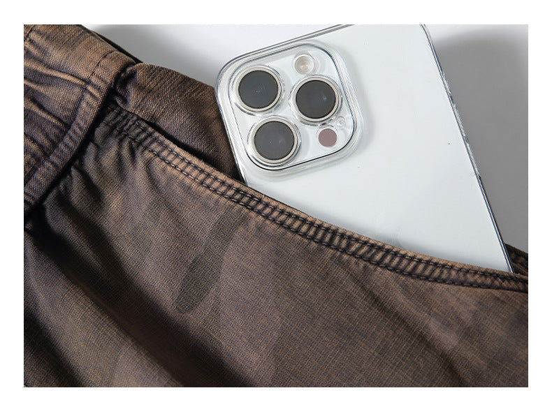 Close-up of brown textured garment fabric and stitched pocket edge with a white smartphone tucked inside.