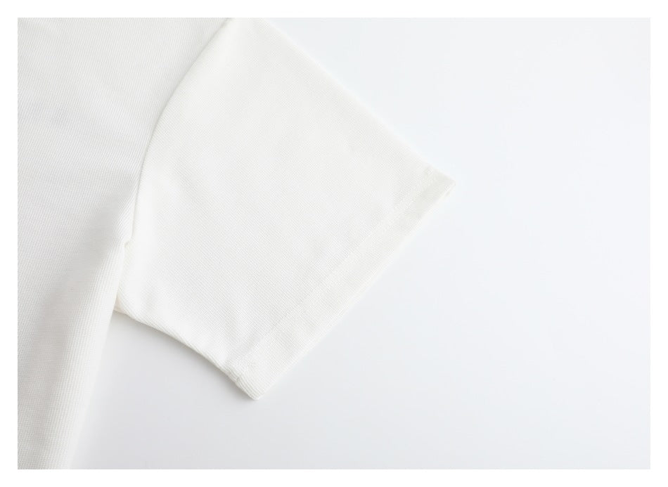 Close-up of a short sleeve and stitched cuff on a white garment.