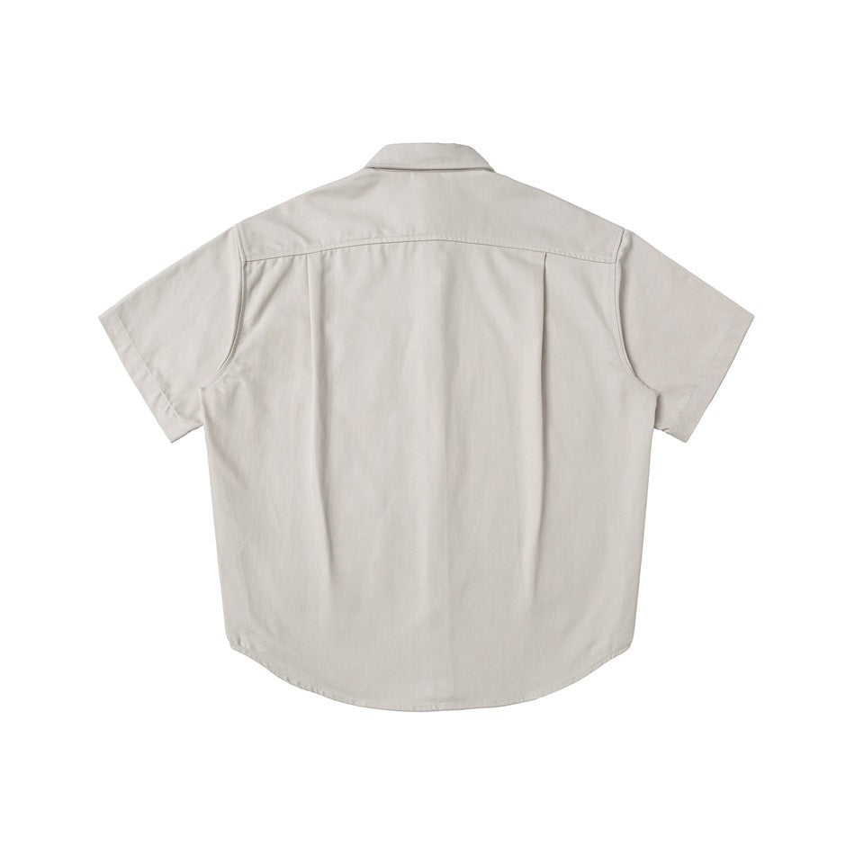 Back view of a light beige short-sleeve collared shirt on a white background.