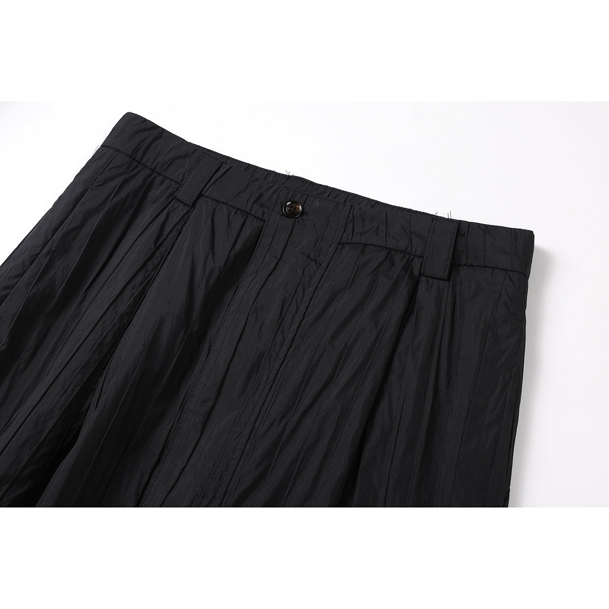 Close-up of black trousers showing the buttoned waistband, belt loops, and front pleats.