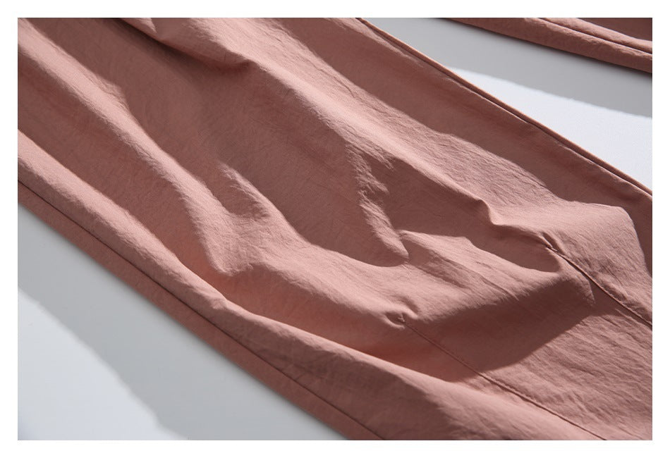 Close-up of dusty rose garment fabric with a stitched seam and softly wrinkled surface.