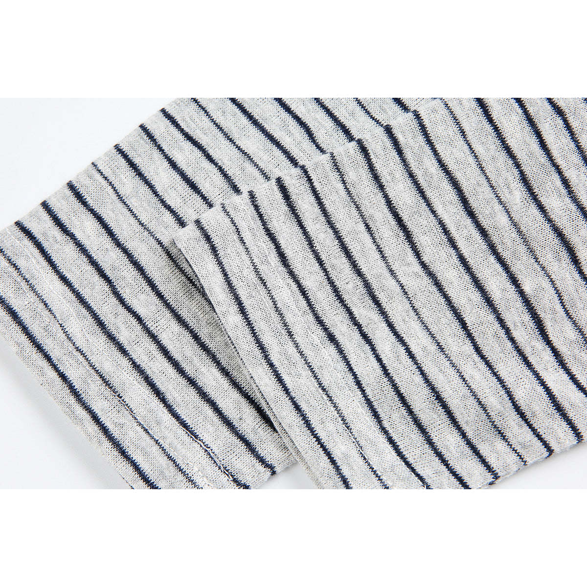 Close-up of a gray shirt with dark stripes, showing a folded sleeve edge and stitching.