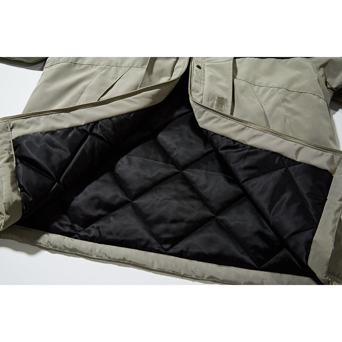 Open khaki jacket showing its black diamond-quilted lining and front zipper.
