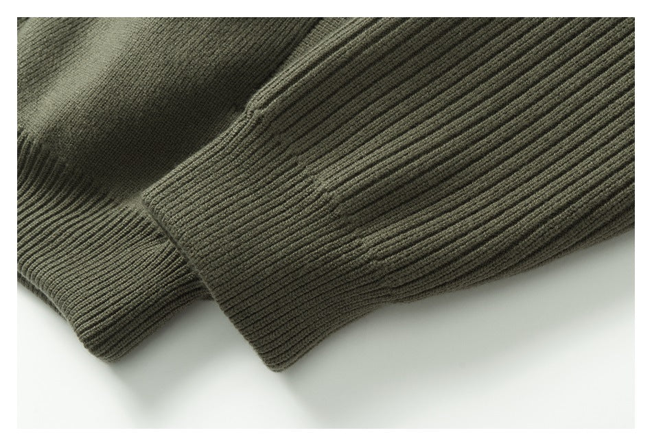 Close-up of a ribbed cuff and sleeve on an olive-gray knit garment.