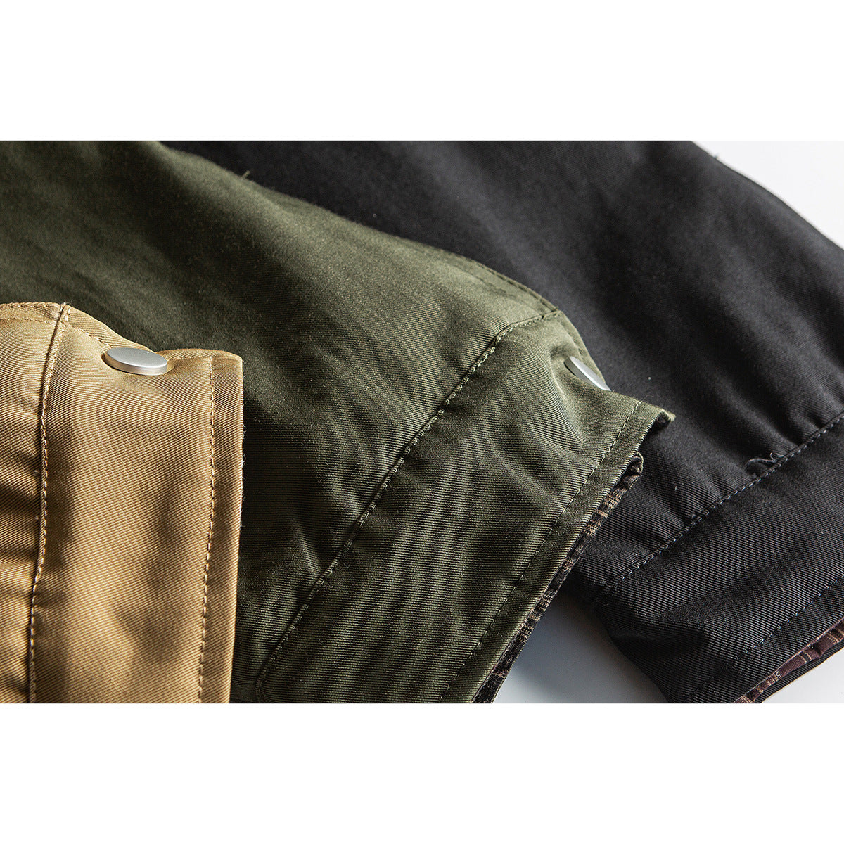 Close-up of jacket cuffs in tan, olive, and black, each with a metal snap.