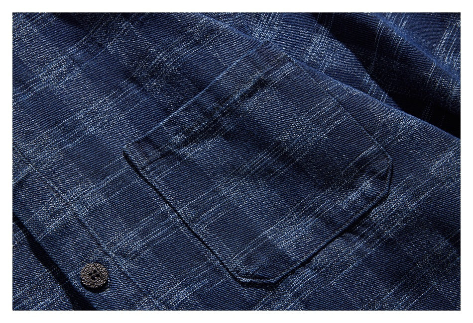 Close-up of a buttoned patch pocket on dark blue plaid fabric.