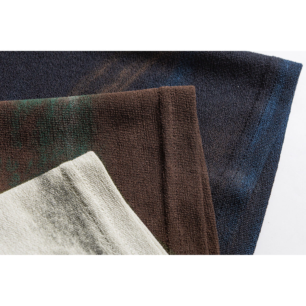 Close-up of textured fabric in navy, brown, dark green, and ivory colorways.
