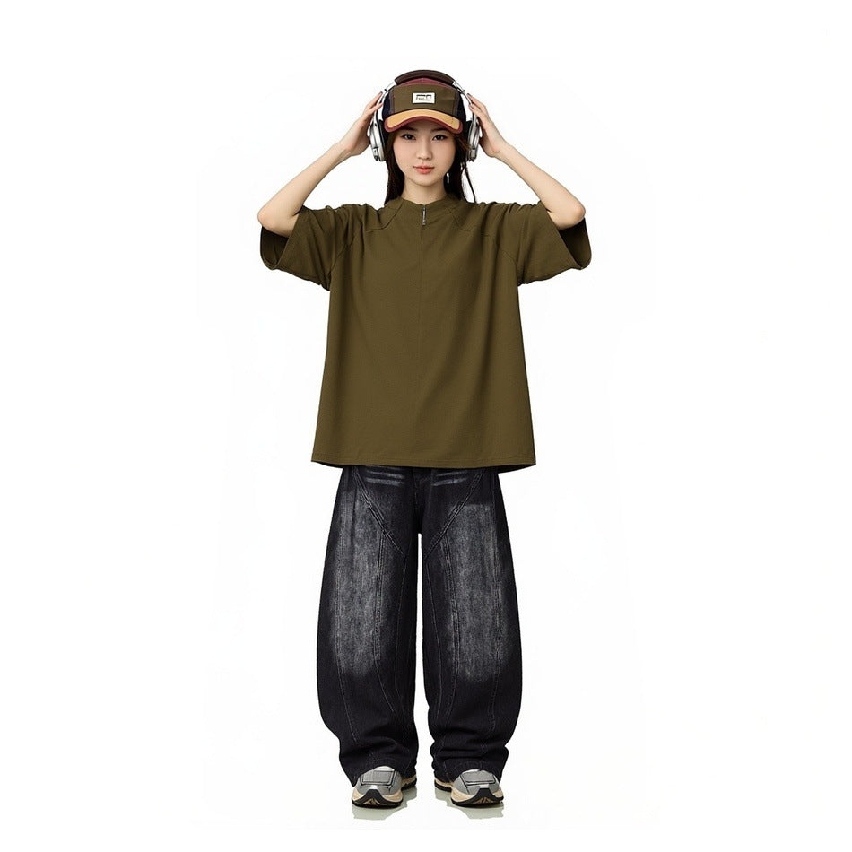 Model wearing an oversized olive short-sleeve zip-neck top with loose black jeans.