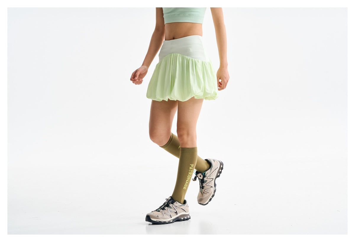 A cropped model wears a pale mint top and a pale lime bubble skirt with a wide waistband.