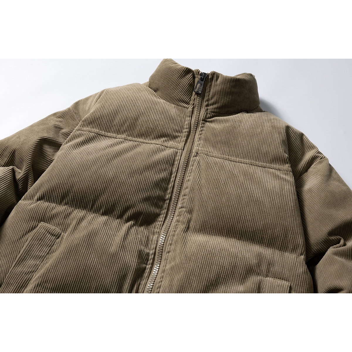 Close-up of an olive-brown ribbed padded jacket with a zip front, stand collar and horizontal seams.