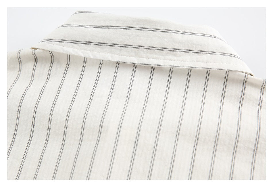 Close-up of a cream garment collar and striped fabric with thin dark vertical lines.