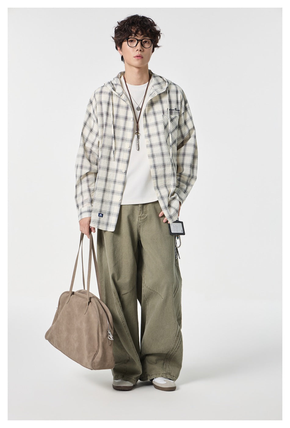 Full-length model wearing a cream and gray plaid hooded button-up shirt with a chest pocket.