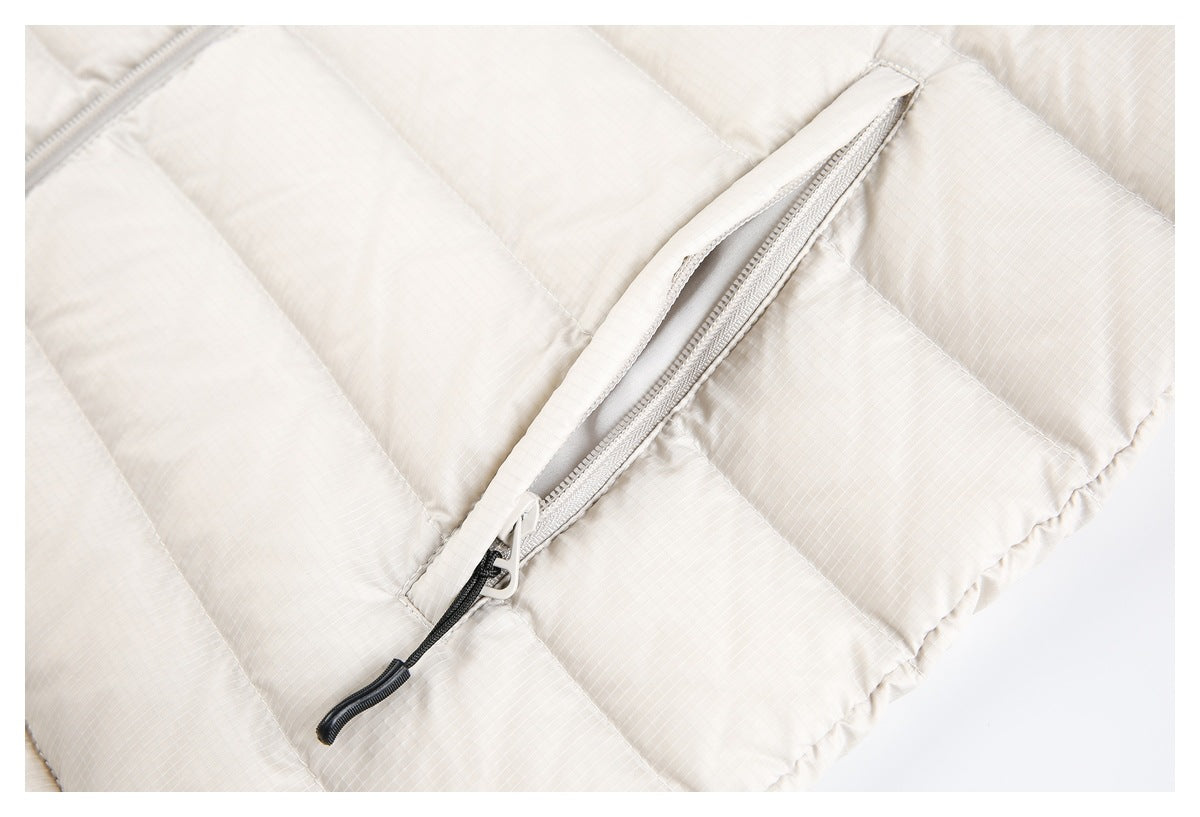 Close-up of a zippered pocket on the off-white quilted jacket, with the zipper partly open.