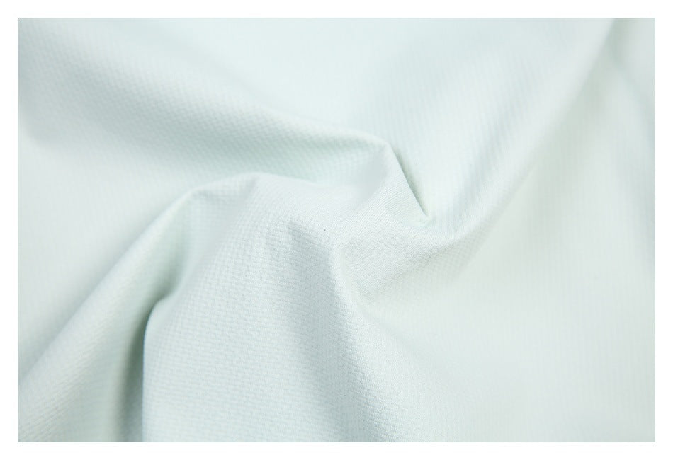 Macro view of the pale mint shirt's subtly textured fabric gathered into soft folds.