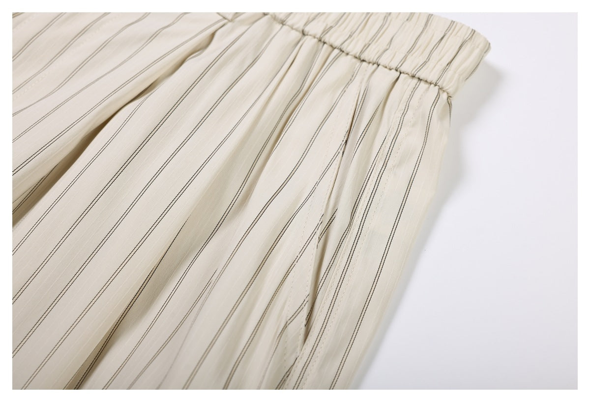 Close-up of cream pinstriped shorts showing the elastic waistband and gathered pleated fabric.