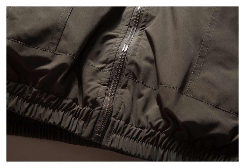 Close-up of the dark taupe jacket's zipper and gathered elastic hem.
