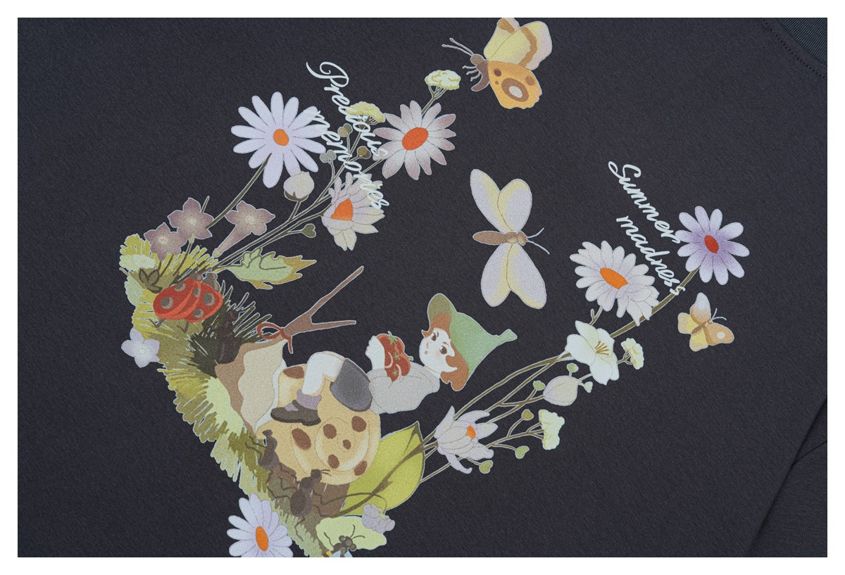 Printed graphic on charcoal fabric featuring flowers, butterflies, a child, and decorative English lettering.
