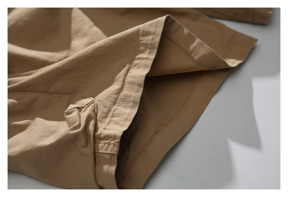 Close-up of the stitched hem and side seam on tan shorts.