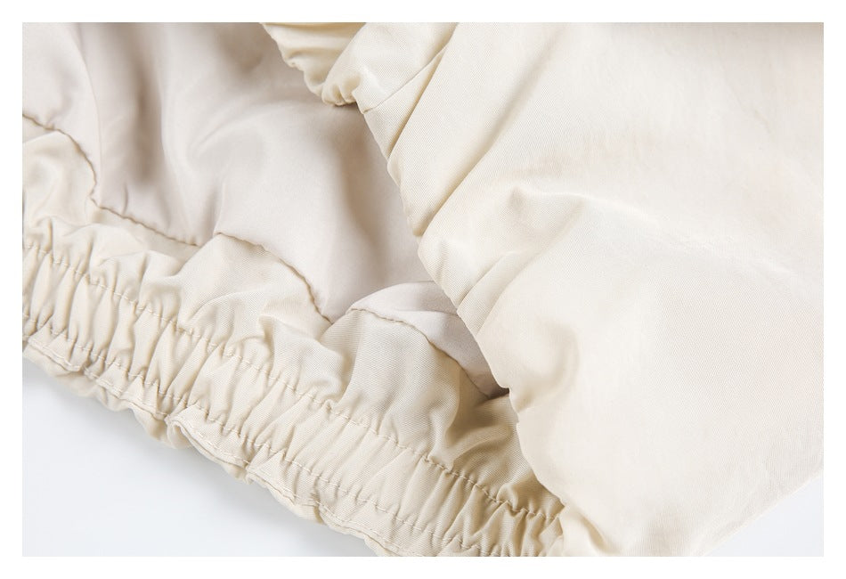 Close-up of gathered elastic hem and stitching on a light beige garment.