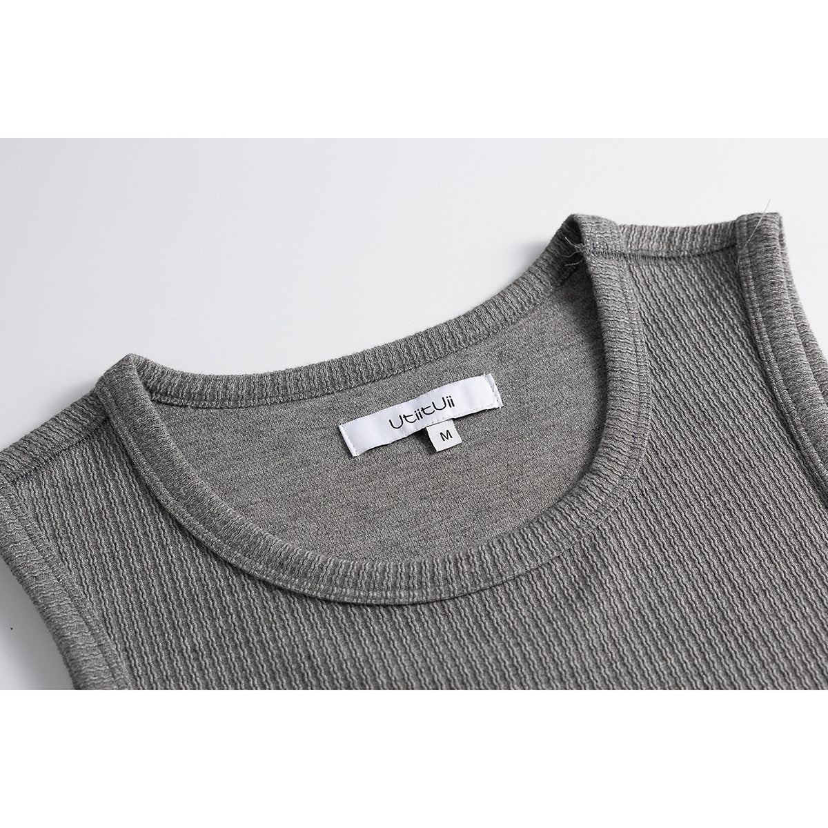 Close-up of a gray ribbed tank top's crew neckline and sewn-in neck label.