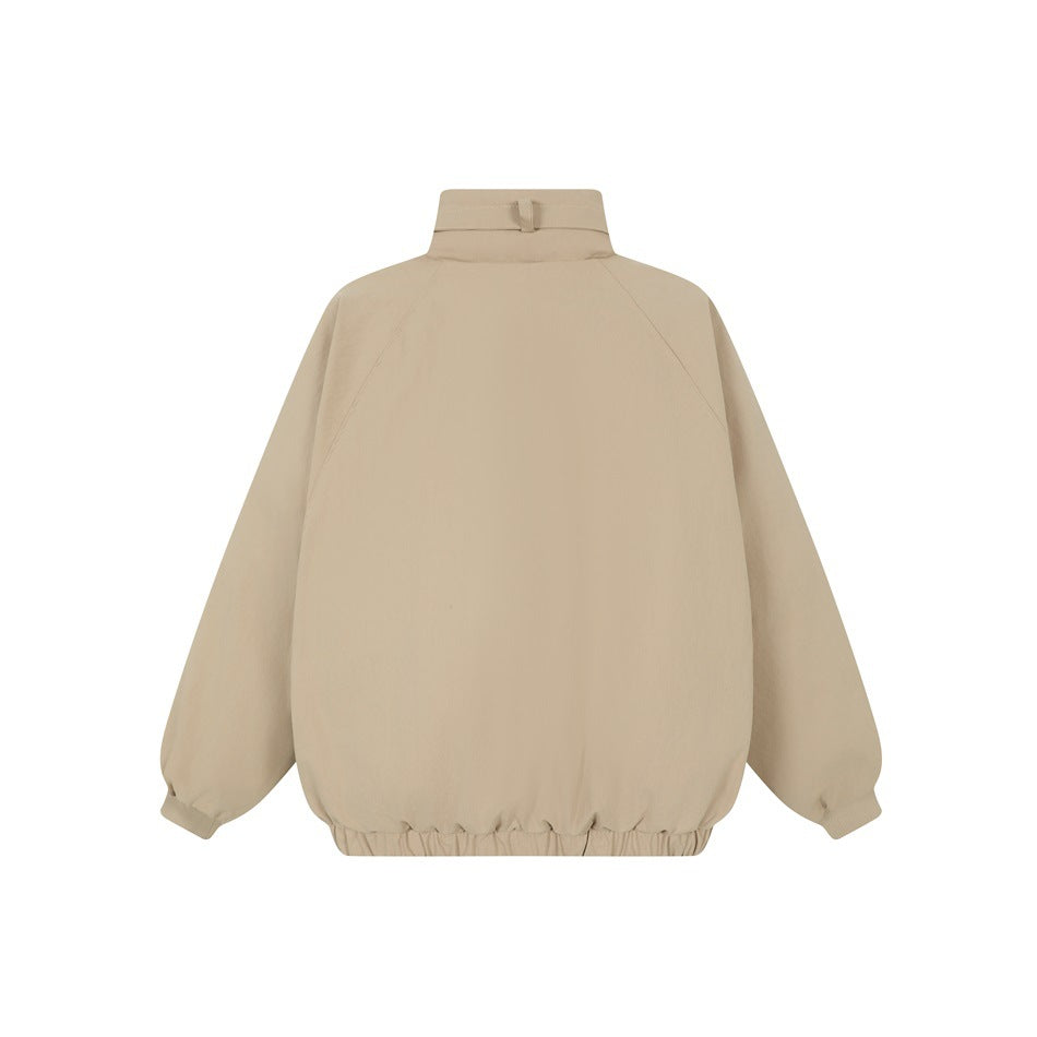 Back view of a light beige jacket with a high collar, raglan sleeves, and gathered hem.