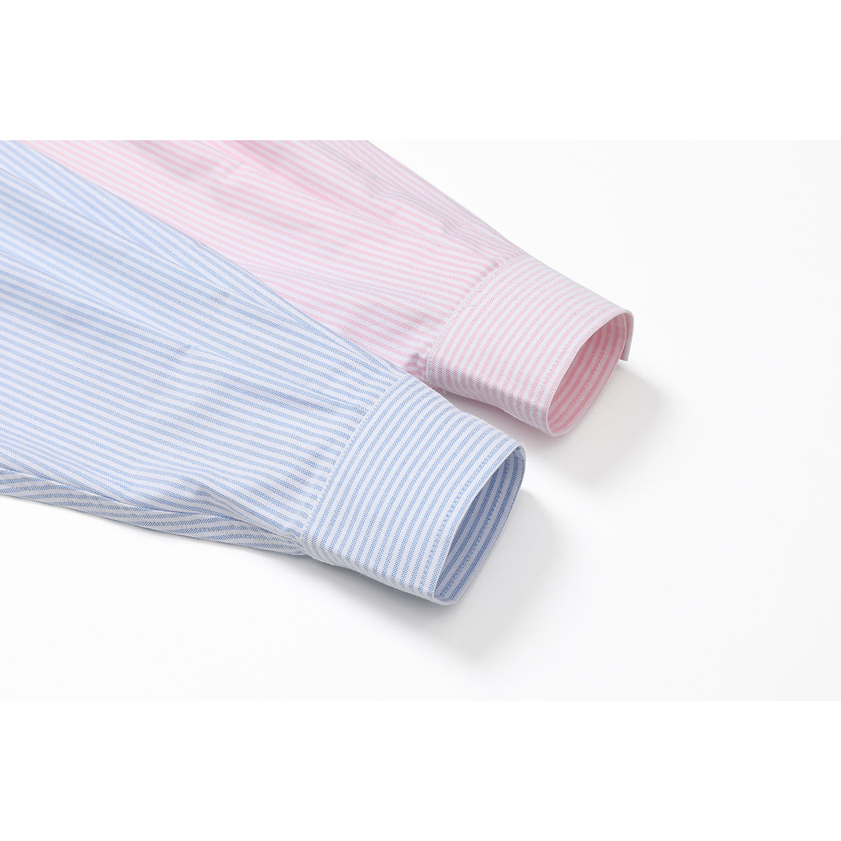 Close-up of the cuffs of pink and light blue pinstriped shirts on a white background.