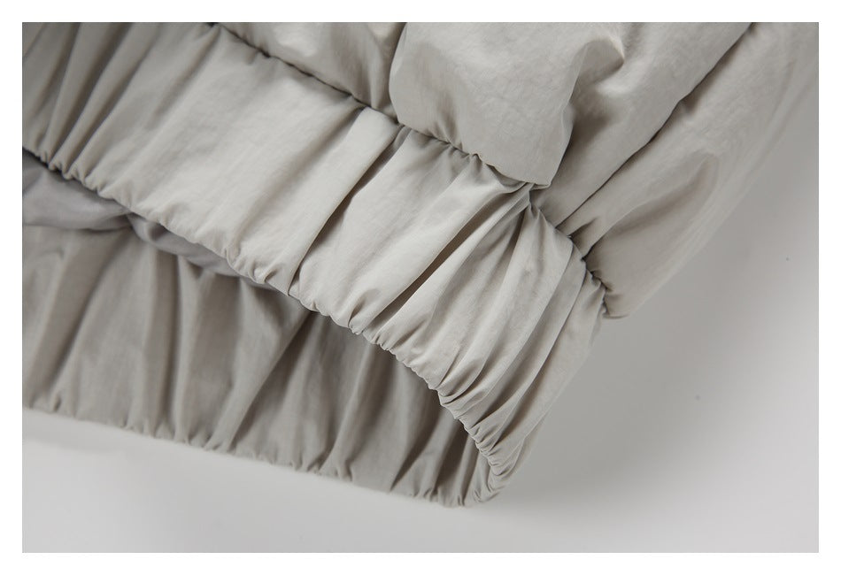 Close-up of the gathered elastic hem on a light gray-beige padded jacket.